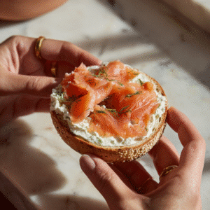 Open Faced Smoked Salmon Bagel: Elegant Breakfast Simplicity in Every Bite 5 Assembling an open faced smoked salmon bagel with cream cheese and dill.