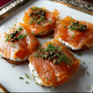 Cold smoked salmon on toast with cream cheese, topped with capers and fresh dill, served on a white platter.